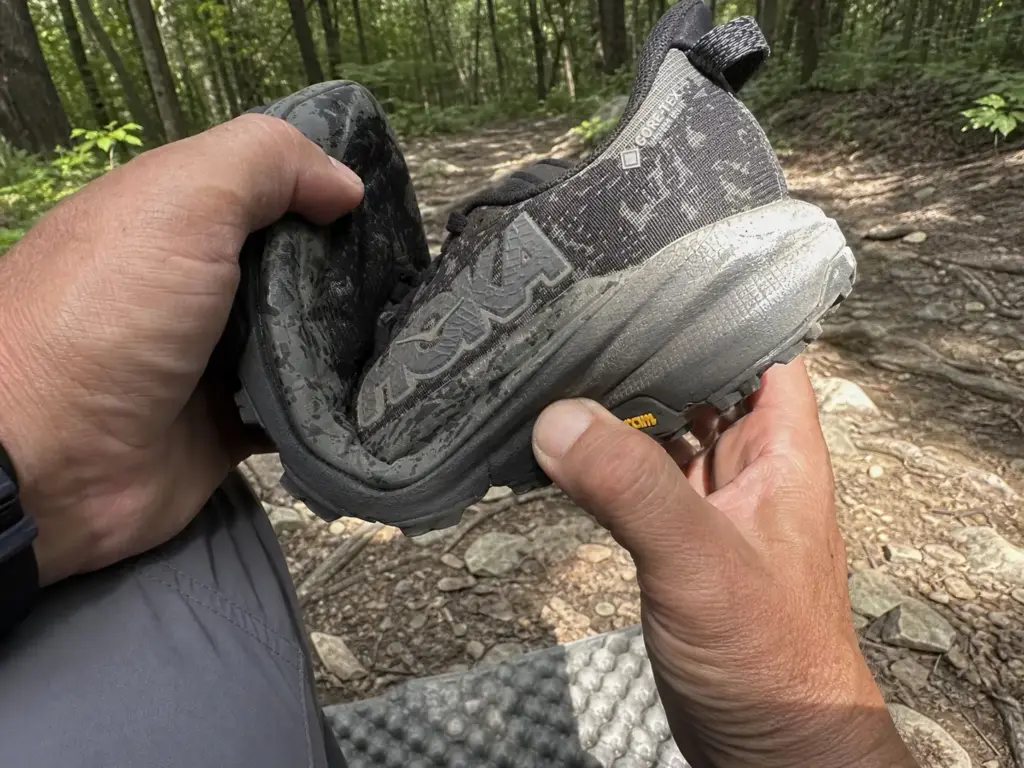 Close-up of hands checking midsole compression on a worn HOKA Speedgoat trail runner