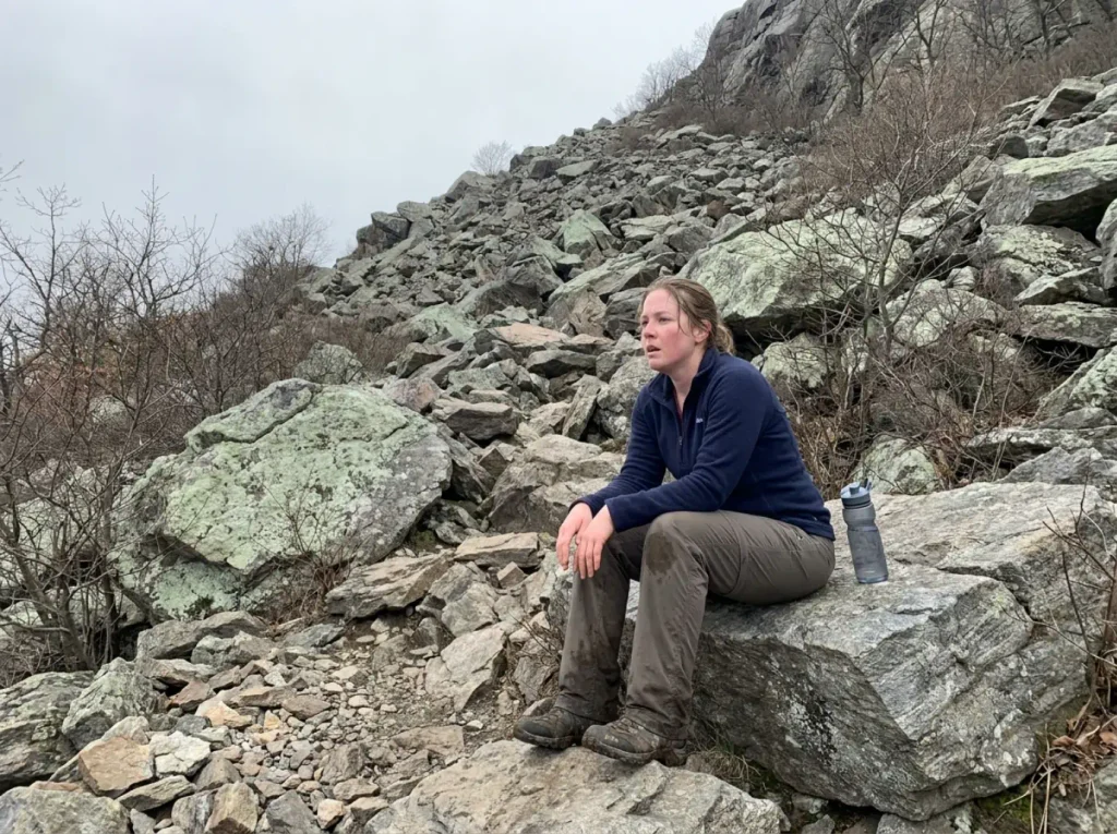 Hiker resting at the base of the steep boulder section on the Breakneck Ridge white trail