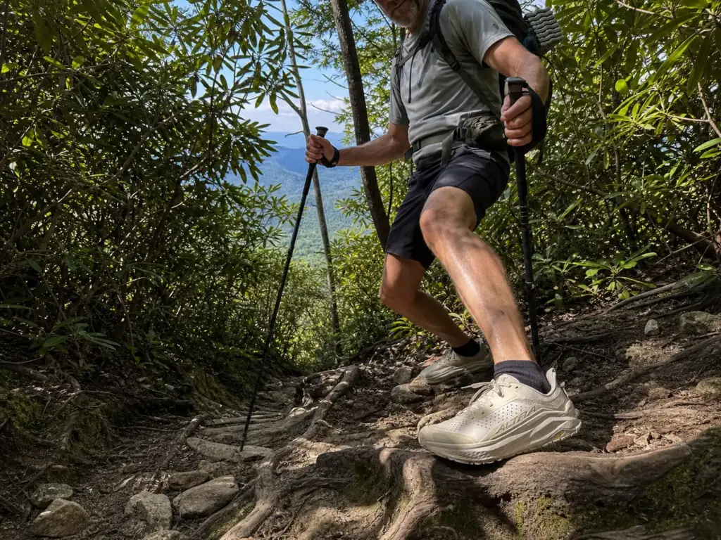 Hiker descending a steep rooty Appalachian trail in zero-drop Altra Olympus trail runners
