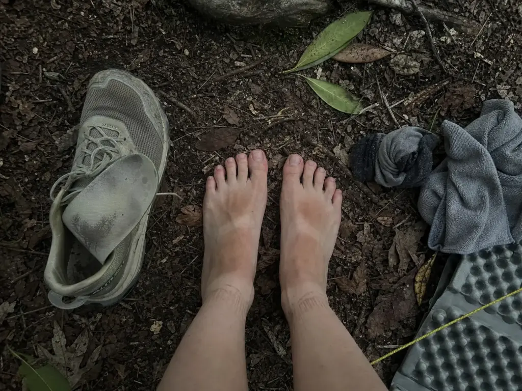Swollen bare feet beside a trail runner at an Appalachian Trail campsite after a long day
