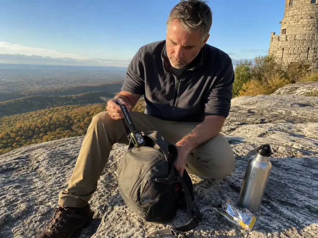 Hiker pulling a Black Diamond headlamp from a daypack on the Shawangunk Ridge at Mohonk