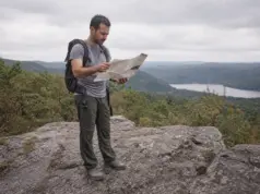 Hikes in North Jersey Sorted by What You Want Hiker checking a paper trail map at a rocky Highlands overlook on a North Jersey hike
