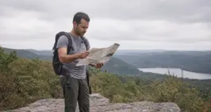 Hikes in North Jersey Sorted by What You Want Hiker checking a paper trail map at a rocky Highlands overlook on a North Jersey hike