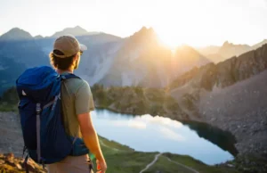 Colorado’s Best Backpacking Loops for Every Skill Level A backpacker overlooks a spectacular Colorado mountain range with an alpine lake at sunrise, about to start a backpacking loop.