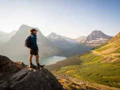 Glacier NP Day Hikes: A Field-Tested Planning Guide A hiker stands on a scenic overlook on the Highline Trail, thoughtfully planning their route while looking out over the mountains and valleys of Glacier National Park at sunset.