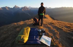 A Hiker’s Core Gear System: From Day Hike to Thru-Hike A thru-hiker and their complete, organized gear system laid out on a mountain pass at sunset, showcasing the evolution from day hiking to advanced backpacking.
