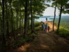 LBL Hiking: Trail Data for Every Skill Level A scenic, wide-angle view of a hiking trail in Land Between the Lakes at sunset, with diverse hikers enjoying the path that winds through forests and up to a lake overlook.