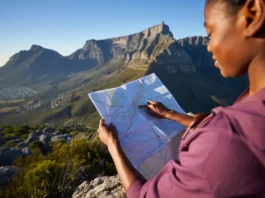 A hiker studies a map while looking out at the full expanse of Table Mountain, planning a data-backed hiking adventure.