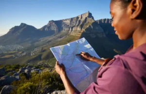 Choosing Your Table Mountain Hike: A Data-Backed Guide A hiker studies a map while looking out at the full expanse of Table Mountain, planning a data-backed hiking adventure.