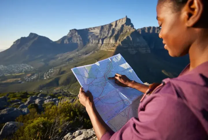 A hiker studies a map while looking out at the full expanse of Table Mountain, planning a data-backed hiking adventure.