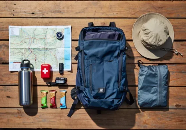 Essential must-have items for a day hike list arranged neatly: daypack, water bottle, map, compass, headlamp, first-aid, snacks, hat, rain jacket.