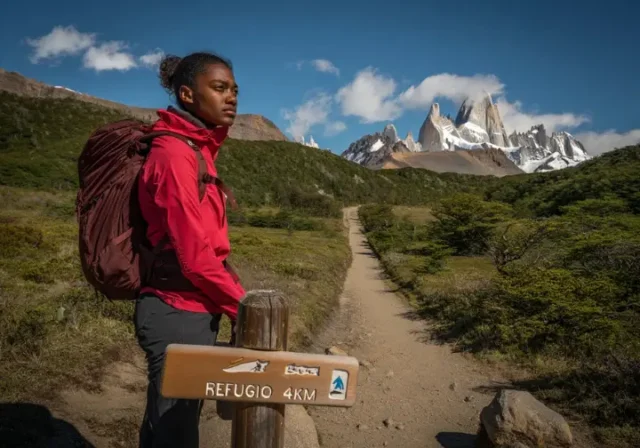 Hiker at a trail junction in Patagonia contemplating the choice between a guided tour route versus hiking independently.