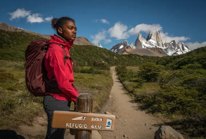 Hiker at a trail junction in Patagonia contemplating the choice between a guided tour route versus hiking independently.
