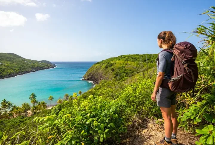 Hiker enjoying a scenic viewpoint on a secret St Thomas hiking trail, looking out over the coastline beyond the beaches.