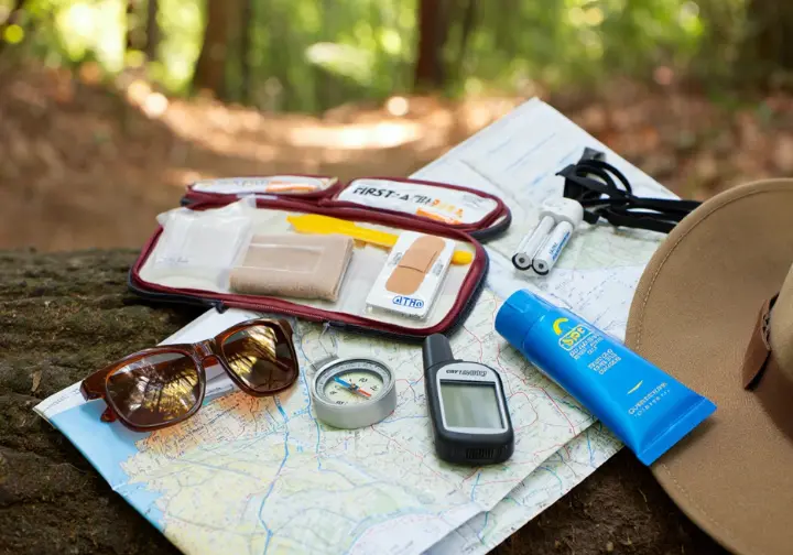 The foundational Ten Essentials for hiking displayed: navigation tools, headlamp, sun protection items, and first-aid kit.