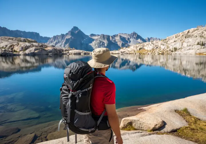 A backpacker looks out over the granite basins and clear water of an alpine lake in Desolation Wilderness, a premier backpacking destination in Northern California.