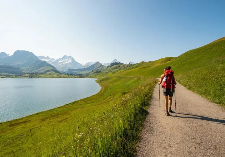 Hiker enjoying an open lakeside hiking path in Switzerland during May, representing accessible low-altitude hike types.
