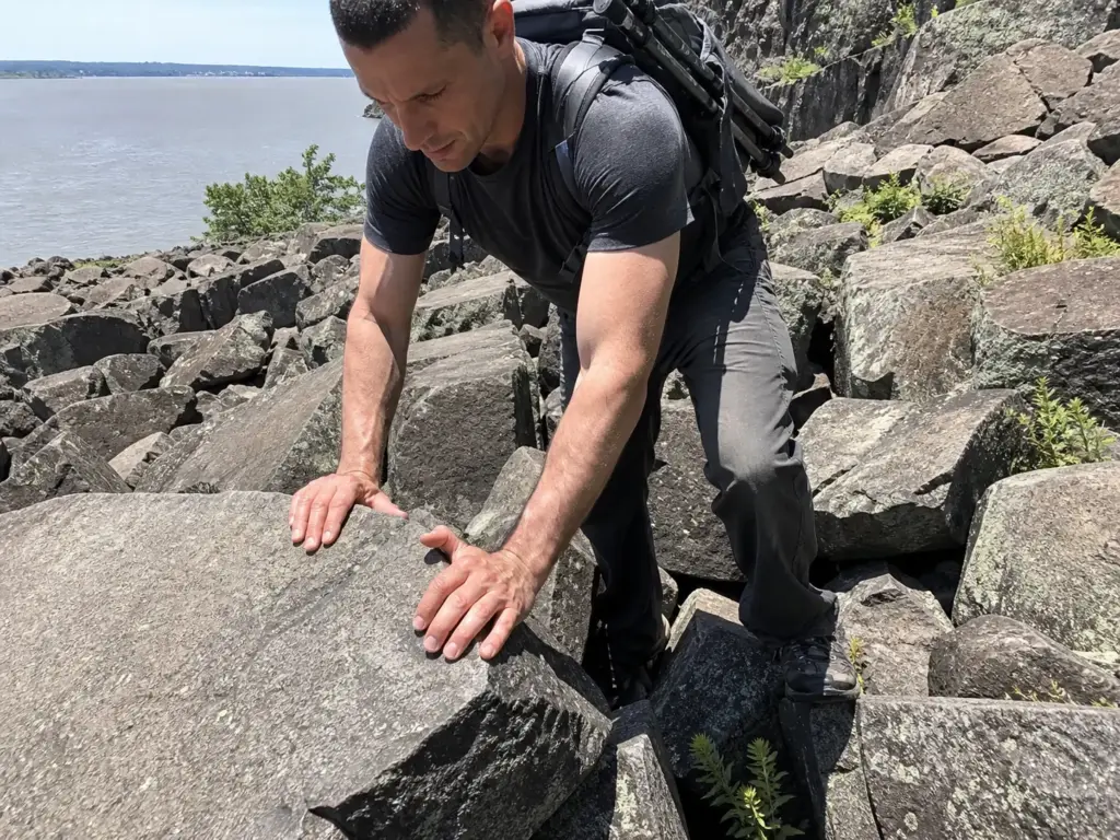 Hiker using both hands to scramble the Giant Stairs boulder field on the Palisades Shore Trail