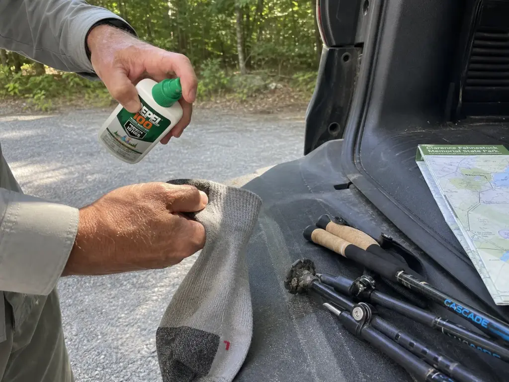 Insect repellent and carbon trekking poles laid out on a tailgate before a Fahnestock hike