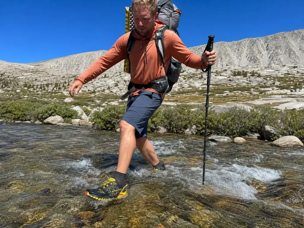 Backpacker crossing a cold stream in mesh trail runners on the Colorado Trail above treeline