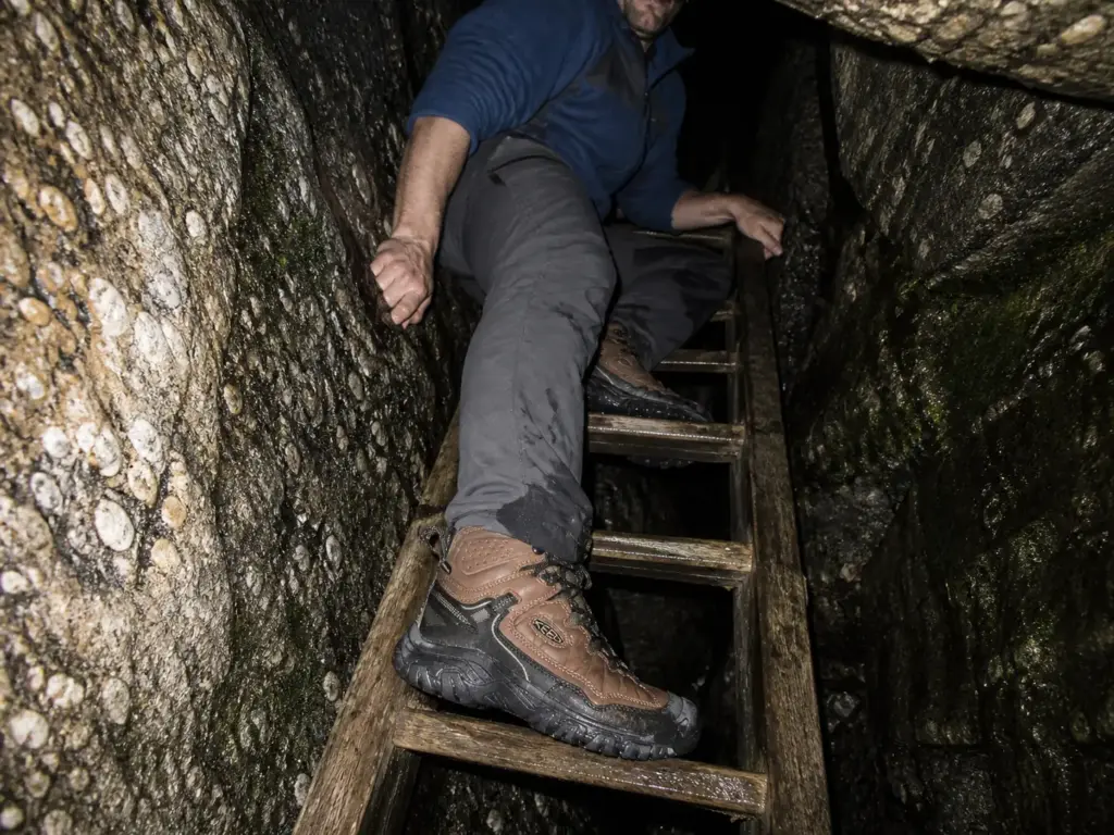 Hiker on a wooden ladder inside the Sam's Point ice caves wearing mid-cut waterproof hiking boots
