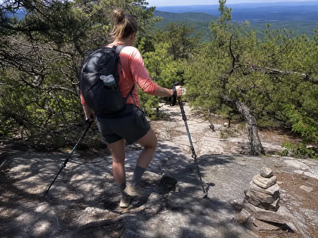 Hiker with trekking poles on the rocky ridge trail toward Verkeerder Kill Falls at Sam's Point