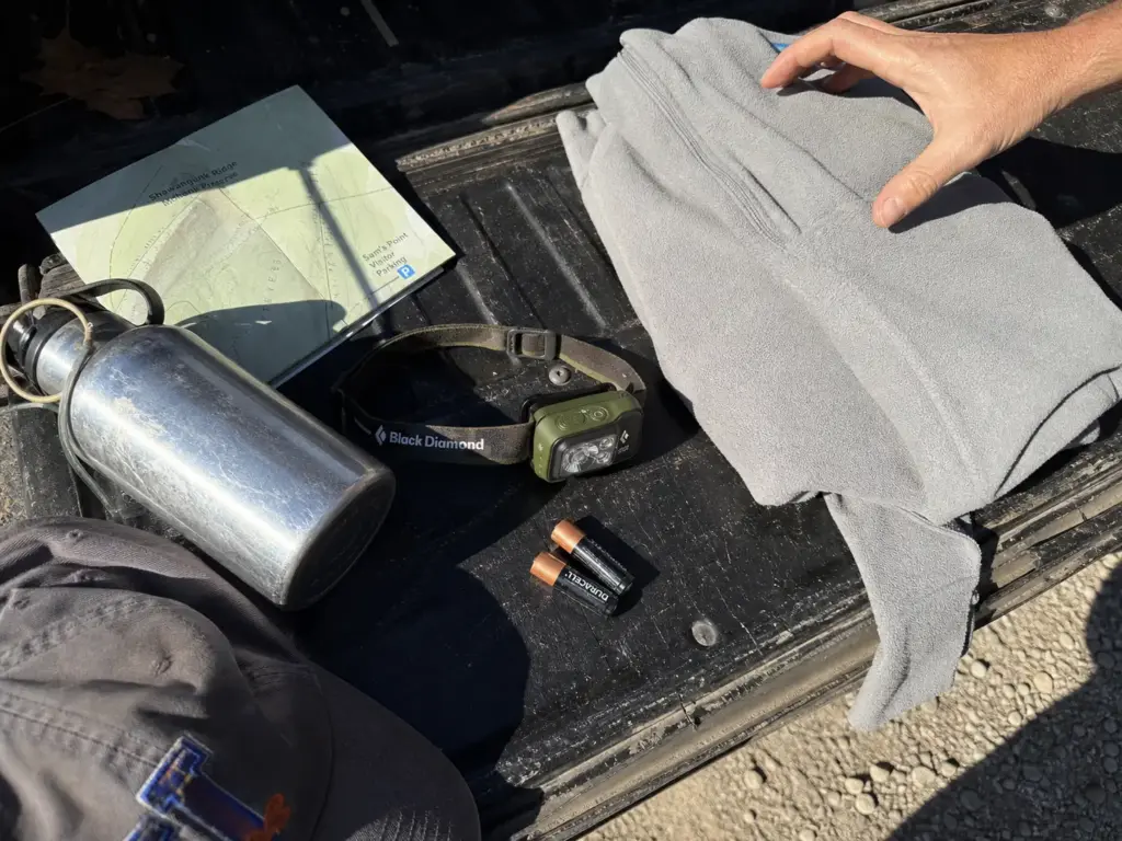 Headlamp, layer and water laid out on a tailgate before hiking the Sam's Point ice caves