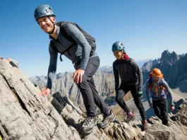 Three alpine scramblers with essential gear ascend a rocky mountain ridge under a clear sky, illustrating non-negotiable equipment for essential gear for alpine scrambling and easy mountaineering.