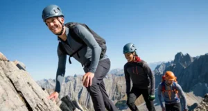 The Non-negotiable Gear for Alpine Scrambling Three alpine scramblers with essential gear ascend a rocky mountain ridge under a clear sky, illustrating non-negotiable equipment for essential gear for alpine scrambling and easy mountaineering.