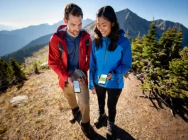 Two hikers on a mountain trail comparing different hiking GPS apps on their smartphones, representing the best hiking apps of 2025.