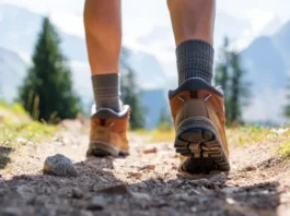 Hiker's feet in boots and socks on a trail, representing a guide to blister prevention and care.