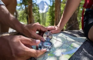 Beyond GPS: Mastering Analog Navigation Skills Hands using a compass and topographic map in a forest, emphasizing mastery of analog navigation skills for hikers.