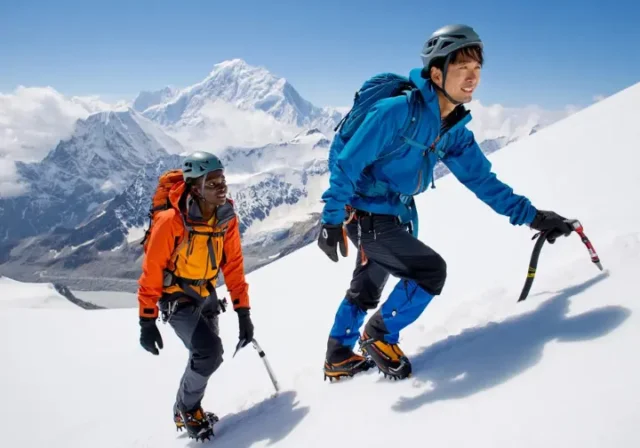 Two hikers with ice axes ascending a snowy mountain, illustrating self-arrest and mountain safety for an introductory guide to stopping falls.