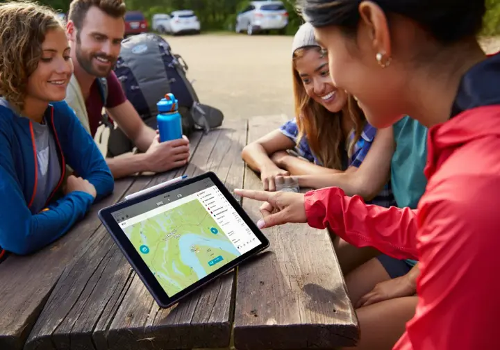 Hikers studying digital maps on a tablet at a trailhead, illustrating the foundational concepts of digital navigation for hiking.