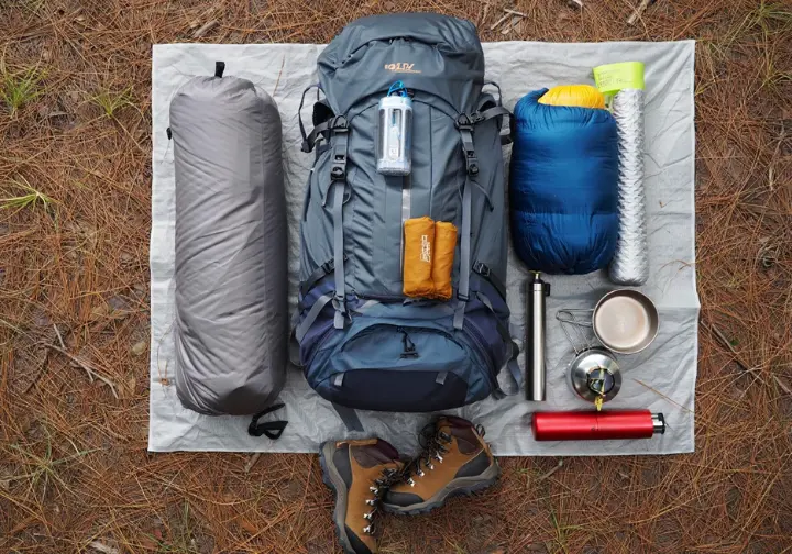 A collection of essential backpacking gear, including a backpack, tent, sleeping bag, and hiking boots, neatly laid out on the ground, representing a beginner's guide to packing for a trip.