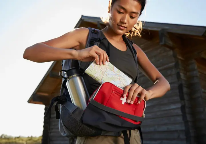 A focused hiker meticulously packs her backpack, demonstrating pre-hike ritual and preparedness.