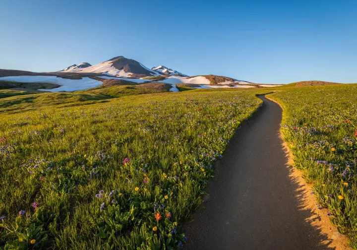 A pristine and well-maintained trail winds through a beautiful mountain landscape, illustrating the positive impact and philosophy of trail stewardship.
