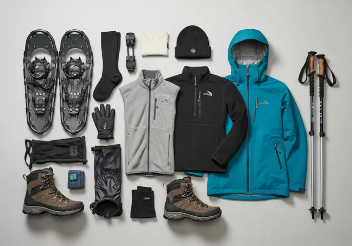 A complete set of snowshoeing gear laid out, including snowshoes, boots, clothing layers, and accessories, for an introduction to snowshoeing.