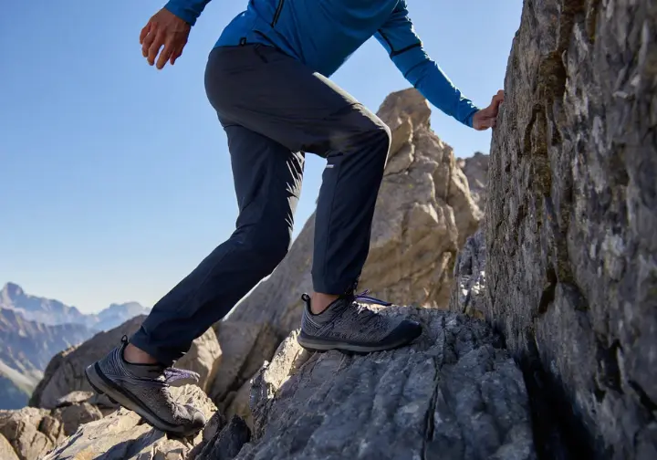 A male hiker demonstrates precise footwork on a rocky outcrop, illustrating essential scrambling skills and techniques.