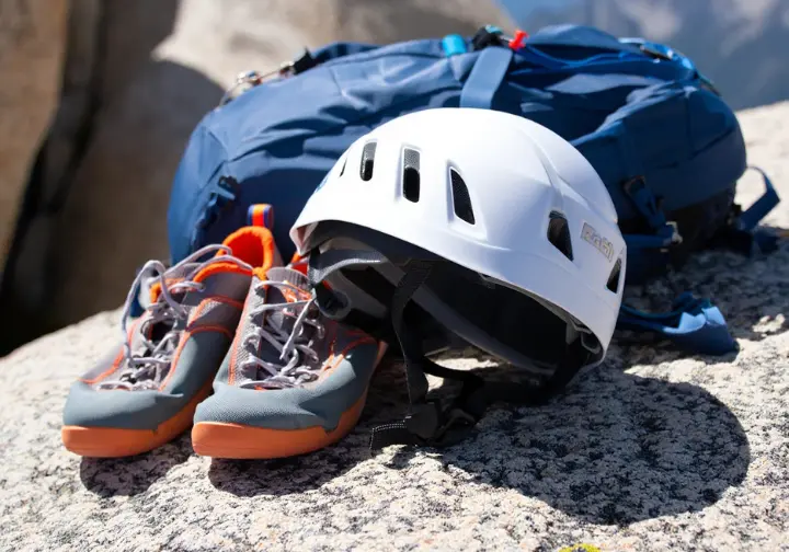 Climbing helmet, approach shoes, and scrambling backpack on rock, showing the scrambler's core kit for essential gear for alpine scrambling and easy mountaineering.