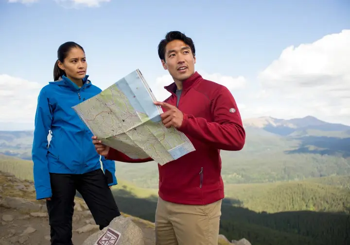 Two hikers at a scenic overlook, symbolizing a mindset of safety and responsibility in the outdoors, with emphasis on trip planning and Leave No Trace principles.