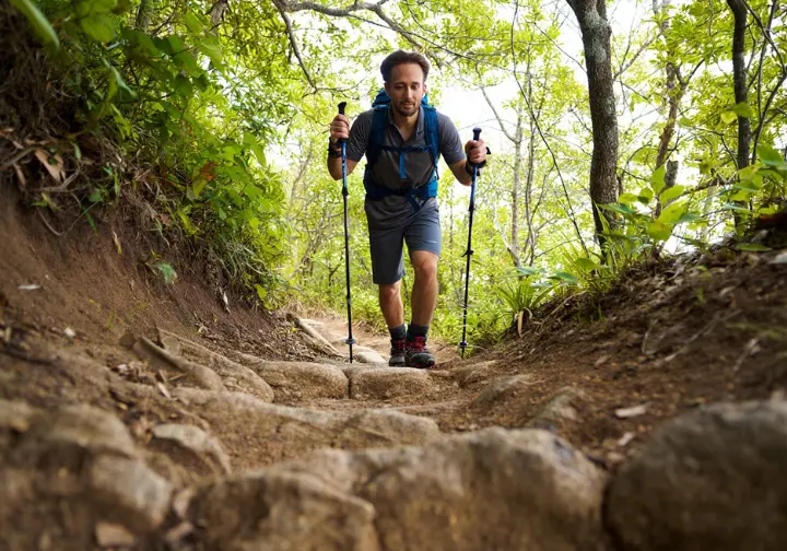 A hiker demonstrating essential trailcraft and safety while navigating a rocky trail.