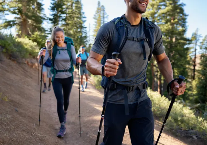 Hikers using trekking poles to maintain rhythm and support on a trail, illustrating the importance of gear, group dynamics, and mindset in purposeful hiking and energy management.