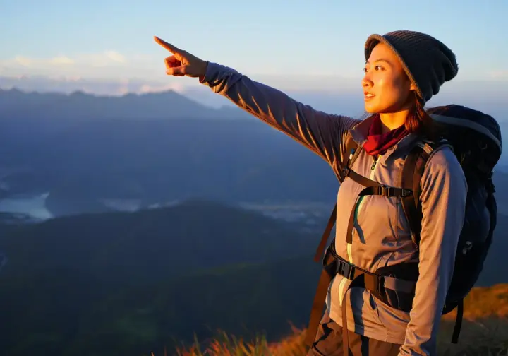 A hiker on a ridge, gazing thoughtfully at the distant landscape, representing the development of a confident navigator's mindset.
