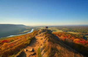 Explore CT: Hikes From Beginner to Expert A stunning autumn view from a hiking trail overlook in Connecticut, with hikers looking out over colorful, rolling hills.