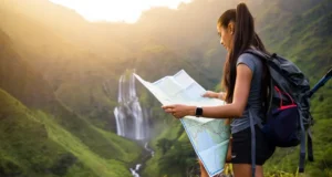 Find a Waterfall Hike: Maps, Gear & Pro Trail Tips A hiker with a backpack and map plans her route while looking out at a stunning, large waterfall in a mountain valley at sunset.