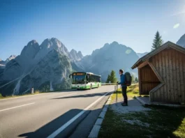 A prepared hiker with a backpack waits at a bus stop on a scenic mountain road in the European Alps, as a local bus arrives to begin a car-free day of hiking.