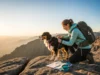 Hiking With Your Dog: A System for Gear, Safety & Rules A hiker and her leashed Australian Shepherd on a scenic mountain overlook at golden hour, demonstrating the system of gear and safety for hiking with a dog.