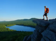 Hiking Giuffrida Park: Trails, Peaks & Essential Tips A hiker stands on the rocky summit of Chauncey Peak, looking at the panoramic view of Crescent Lake and Lamentation Mountain in Doctor Francis Giuffrida Park, Meriden, CT.