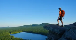 Hiking Giuffrida Park: Trails, Peaks & Essential Tips A hiker stands on the rocky summit of Chauncey Peak, looking at the panoramic view of Crescent Lake and Lamentation Mountain in Doctor Francis Giuffrida Park, Meriden, CT.